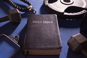 Bible Surrounded by Various Gym Equipment