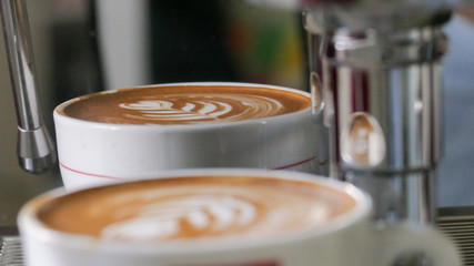 detail of prepared cappuccino with latte art on a coffee machine, coffemaker (color toned image)