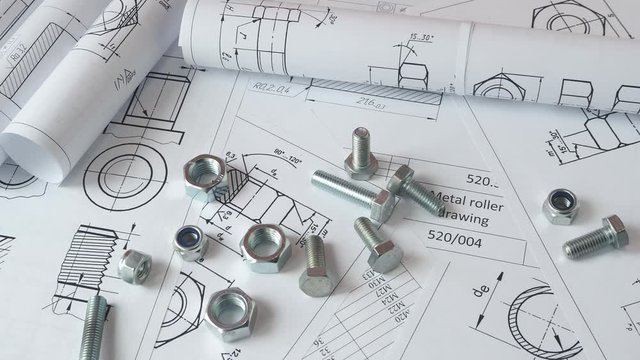 Technical drawings of bolt and nut. Engineering, technology and metalworking. Metal bolt and nut on printed drawings background.	