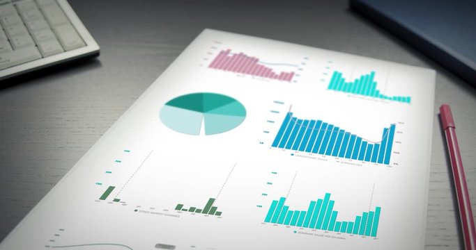 Smooth pan over paper on office table with digitally animated graphs and diagrams