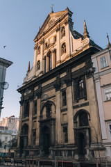 Fototapeta na wymiar Jesuit Church in Lviv. Antique baroque facade with windows by decorative stucco on a beige wall with capitals and with sculptures of the Holy Fathers and the Blessed Virgin Mary in niches.