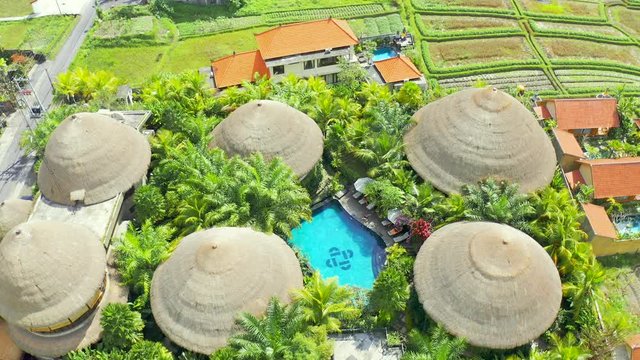 Morning in the wooden bamboo house, enjoy tropical vacation on Bali island. Relax on open-air of bungalow with tropical garden view and pool. Aerial view 4K.
