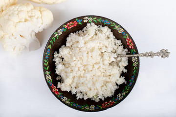Paleo organic vegetarian food cauliflower rice in a floral rustic bowl, on white background