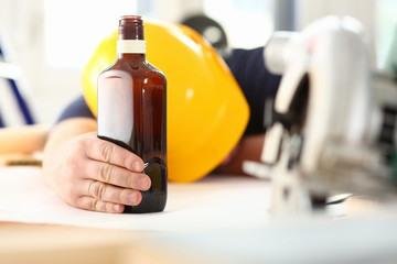 Arm of drunken worker in yellow helmet hold liquor