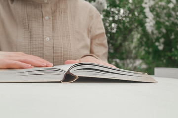 Woman reading a book in the evening. Close-up of person reading a book at the table. 