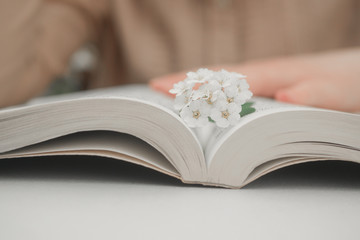 Woman reading a book in the evening. Close-up of person reading a book at the table. 