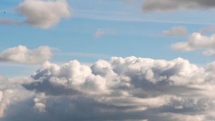 The clouds in the sky. White, fluffy and long Cumulus clouds illuminated by the rays of the sun in the blue sky. Heaven. Cloudy weather on a Sunny summer day. Template. 