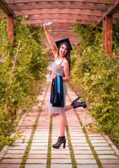 Woman taking a lot of different graduation photos in a beautiful botanical park.