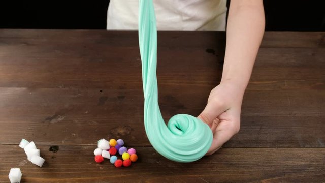 Green slimy toy in the hands of children on a blue background. To make the slime. Copyspace. Flatley.