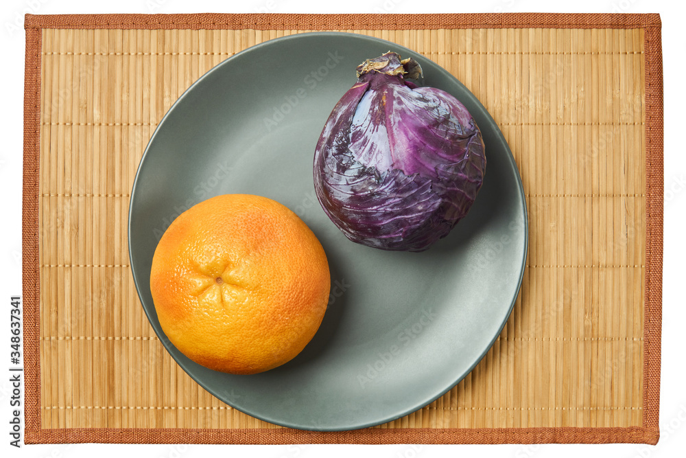 Wall mural purple head of red cabbage and rosy yellow grapefruit on a gray plate on a cane tablecloth