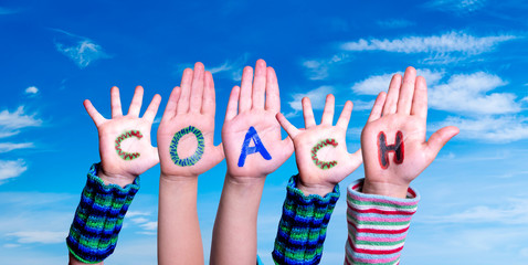 Children Hands Building Colorful Word Coach. Blue Sky As Background