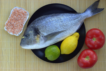 
Fish dinner set: dorado, lemon, lime, tomatoes, basil and parsley. Cooking in a pandemic at home