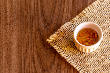 Pepper and olive oil in bowl on wooden background