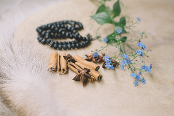 Closeup of decorative materials spices, cinnamon, lavender, forget-me-not flowers, acorns with a rosary over a shaman drum 