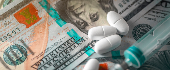 Buying and selling medicines. Vials of medicine and an empty syringe on hundred-dollar bills, Closeup. Template.