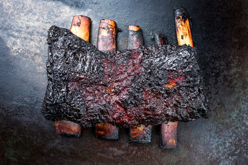 Gegrilltes verbranntes amerikanisches Chuck Beef Rib mariniert mit scharfer Chili Sauce als Draufsicht auf einem alten rustikalen Metall Board - obrazy, fototapety, plakaty