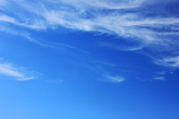Cloudy blue sky background. Light white color clouds on vivid blue sky texture background, cloudscape nature wallpaper. Outdoor summer day view on clear windy day