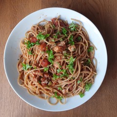 pasta dish chicken with tomato sauce and parsley in a white bowl on a wooden table