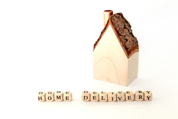 House wooden model with 'home delivery' written nearby on white background and copy space