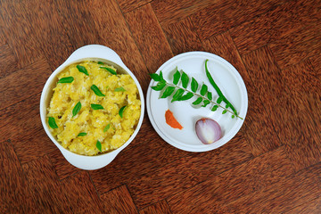 Tasty south indian kappa puzhukku, cooked tapioca in a white bowl isolated on wooden background