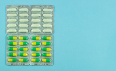 White and yellow-green capsules on a blue background. Four packs of capsules. The concept of the pharmaceutical industry. Pharmacy. Disease Prevention