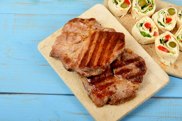 grilled meat on a kitchen board with pieces of colorful tortilla