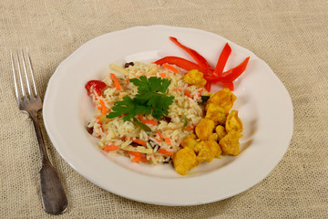 pieces of fried chicken in curry with rice and vegetables on a white plate