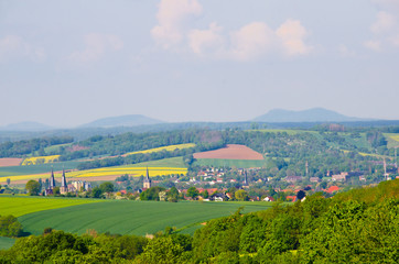 A german landscape with yellow fields of rape, in the middle of Germany, Europe, with some hills and a small village