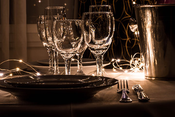 primer plano de mesa con platos cuchillo tenedro copas y luces led 