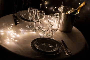 primer plano de mesa con platos cuchillo tenedro copas y luces led navidad año nuevo 2020 2021