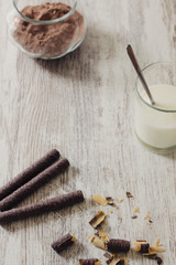 Chocolate waffles, cocoa powde and a glass of milk on a rustic wooden background, as a breakfast or sweet dessert, selective focus
