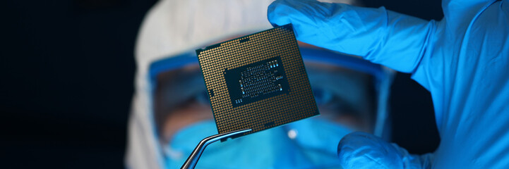Man in uniform holds microprocessor with forceps