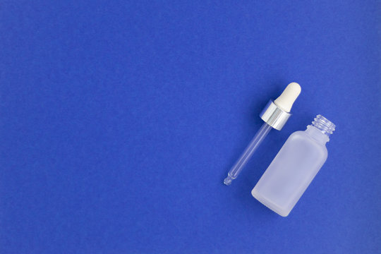 A bottle for collagen moisturizing hyaluron serum on indigo background. Colour of the year.
