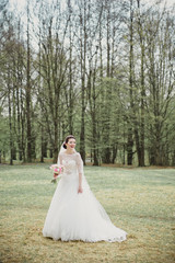 Smiling bride in a white dress with a pink bouquet. Wedding in the spring