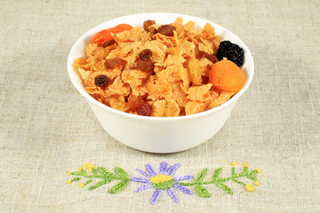 close up of muesli with dried fruits and yogurt in bowl on white background