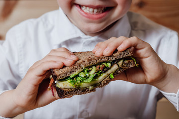 close up, child with vegetarian sandwich with whole grain bread, cucumber, egg whites, radishes and...
