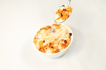 close up of muesli with dried fruits and yogurt in bowl on white background