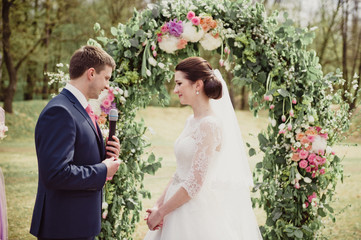 Classical wedding in the spring. Ceremony. The groom says the promise and holds the ring in his...