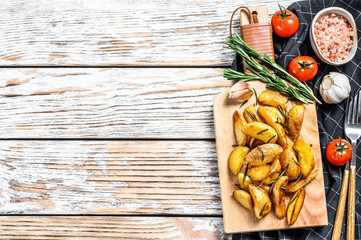 Roasted potato wedges with rosemary and salt. Tasty spicy potato. White background. Top view. Copy space