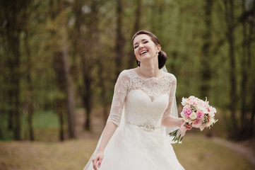 Fototapeta na wymiar Smiling bride in a white dress with a pink bouquet. Wedding in the spring