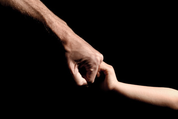 Fototapeta na wymiar Father and son fist bump on black background with outstretched arms