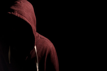 Fototapeta na wymiar Faceless man in a hoody in dark shadows to disguise face