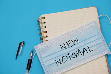 "New Normal" is written in a book with a blue background, New Normal concept.