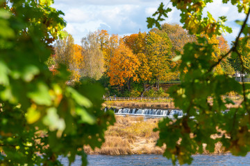 Obraz premium View of the Rumba waterfall in Kuldiga in the fall. Colorful leaves. Beautiful landscape in Latvia.