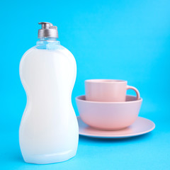 Clean washed tableware. Concept of washing dishes. Dishwashing liquid with plates and cups on blue background...
