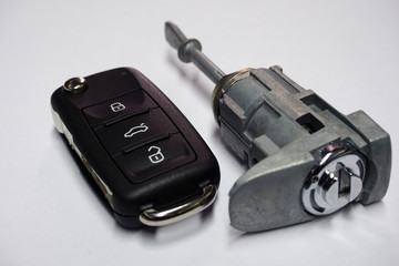 New folding ignition key with three buttons of the anti-theft control system for a modern car and a new cylinder lock on a white background. Ensuring the safety and security of the car. Quality parts.