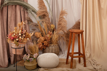 Interior of house is decor in brown tones: wooden chair, knitted pouf, wicker baskets, vases with dried flowers and pampas grass. Dried flowers and vegetation in home interior. Scandinavian cozy decor © stock_studio