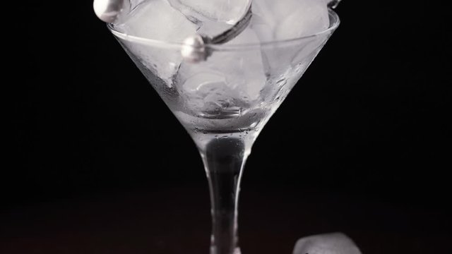 Glass goblet with ice cubes and precious jewelry. Time lapse ice is melting. Close up of silver earrings and chain with ice cubes. Concept for sales and price cuts.