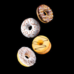 Set of flying glazed donuts with sprinkles on a black background