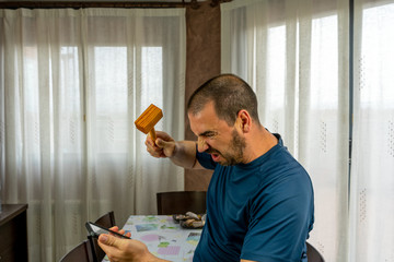 Fototapeta premium Furious man with a beard and short hair in a navy blue shirt throwing his mobile